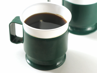 イメージ写真: コーヒーの入った紙コップにホルダーが装着されている